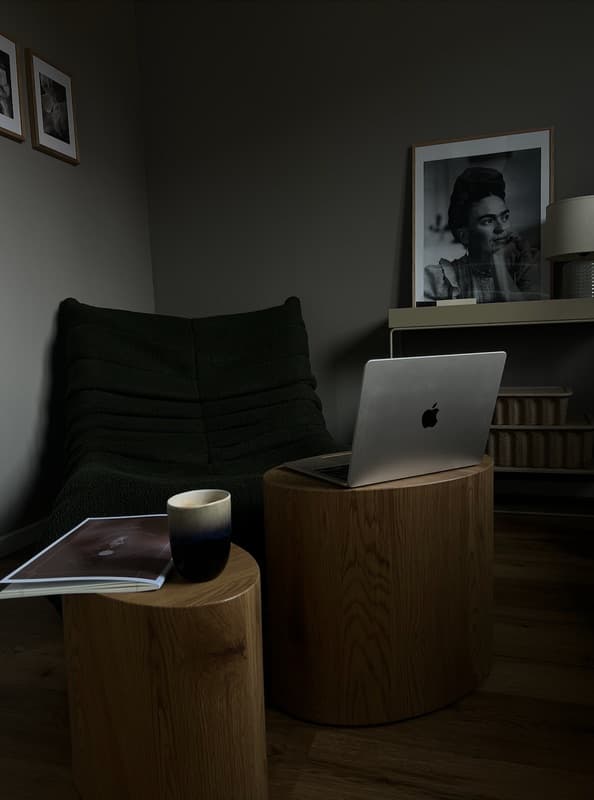 Ruhige Leseecke mit Sessel, Laptop auf einem Holzhocker und einem gerahmten Porträt an der Wand