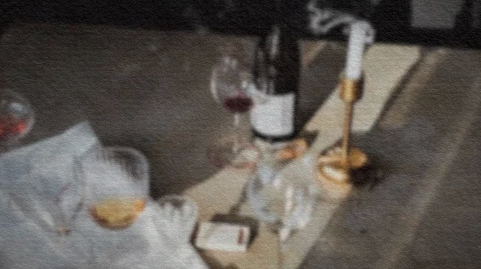 Gedeckter Tisch nach dem Essen: Weinglas, Flasche, eine soeben gelöschte Kerze